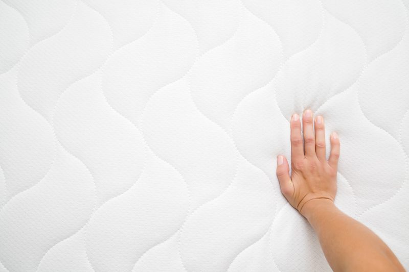 hand pressing down on a memory foam mattresses - benefits of the memory foam mattress